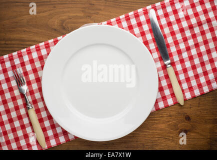 Leeren Teller mit Gabel und Messer auf Tischdecke über Holz Stockfoto