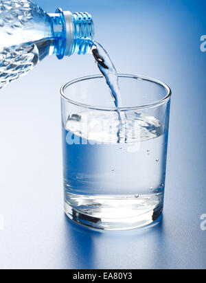 Wasser aus Kunststoff-Flasche, in Glas gießen Stockfoto
