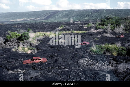 Drei alte verrostete Autos bleiben entlang einer Straße bedeckt von Lava aus einem Vulkanausbruch in the1980s auf der Big Island von Hawaii, USA. Stockfoto