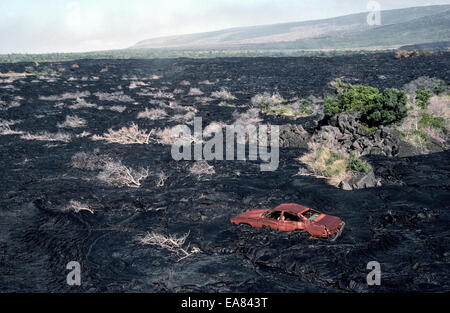 Ein altes rostiges Auto bleibt entlang einer Straße bedeckt von Lava aus einem Vulkanausbruch in the1980s auf der Big Island von Hawaii, USA. Stockfoto