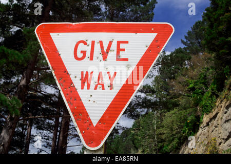 Geben Weg Straßenschild voller Einschusslöcher Stockfoto