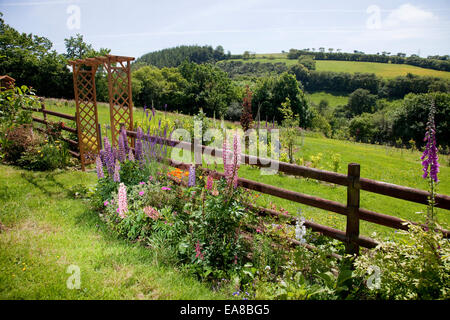 Abfallenden Garten mit Blumen, einem Bogen und einem Blick, inmitten einer schönen englischen walisischen Landschaft in Carmarthenshire, Wales. Es gibt Stockfoto