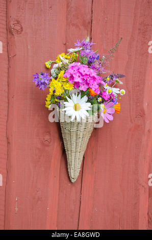 schöne Sommerblumen in Weidenkorb auf Dorf Bauernhof Hauswand Stockfoto