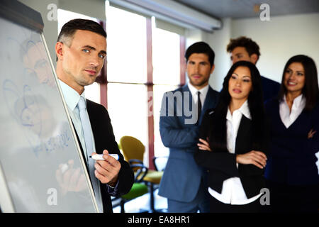 Unternehmer, die etwas auf dem Flipchart, seine Kollegen erklären Stockfoto