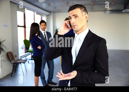 Zuversichtlich Geschäftsmann am Telefon vor Kollegen sprechen Stockfoto