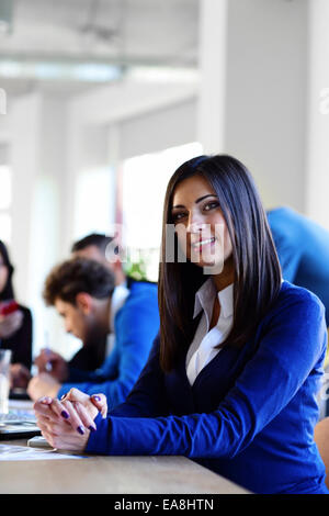 Gerne schöne Busiesswoman auf einer Sitzung am Tisch sitzen Stockfoto