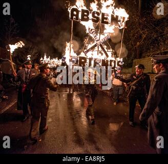 Lagerfeuer-Prozession zur Erinnerung. Zuschauer säumten die Straßen von East Sussex Dorf von East Hoathly in der Nähe von Lewes letzte Nacht Uhr Feuer Banner in Flammen als einen Akt der Erinnerung auf dem Weg in eine riesige Holzskulptur Lagerfeuer und Feuerwerk Anzeige durchgeführt. Die Karneval-Gesellschaft hat Dorfbewohner erinnert seit 90 Jahren in der ersten und zweiten Weltkrieg gefallen. Ein Feuer-Banner mit dem Titel "Freunde" Stockfoto