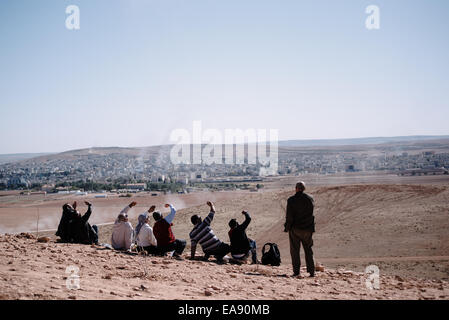 Kurdische Flüchtlinge sehen die alliierten Luftangriffe in Kobani von einem Hügel an der türkischen und syrischen Grenze, Türkei Stockfoto