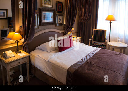 luxuriöse Hotelzimmer mit einem Bett bedeckt eine braune Jacke mit roten Kissen Stockfoto