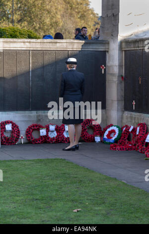 London, UK, 9. November 2014, Remembrance Sunday Mohn Anzeige auf den Tower of London. Eine Service-Frau sieht Gedenktafeln und Mohn Kränze. Das Tower Hill Denkmal erinnert an Männer und Frauen der Handelsmarine und Flotten in beiden Weltkriegen gestorben und haben keine bekannten Grab. Es ist in den Garten von Trinity Square, gegenüber der Tower of London. Bildnachweis: Imageplotter Travel Photography/Alamy Live-Nachrichten Stockfoto