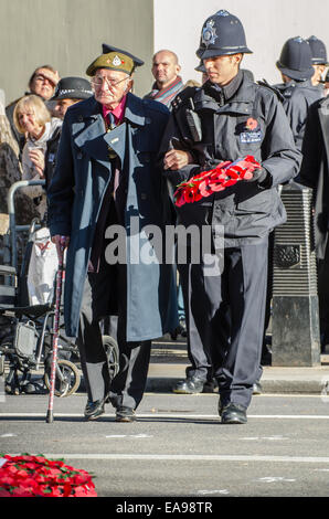 Ein älterer Soldat, unterstützt von einem Polizisten am Ehrenmal einen Kranz während der jährlichen nationalen Dienst der Erinnerung an 11:00 Uhr Erinnerung Sonntag Stockfoto