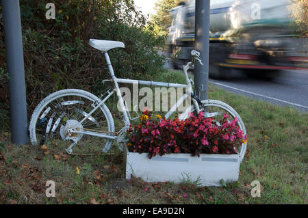 Gefahr. Ein weiß lackiert Ghost Bike und Blumen, die Kennzeichnung der Stelle, wo ein Radfahrer getötet oder bei einem Verkehrsunfall verletzt wurde. Dorset, England Stockfoto