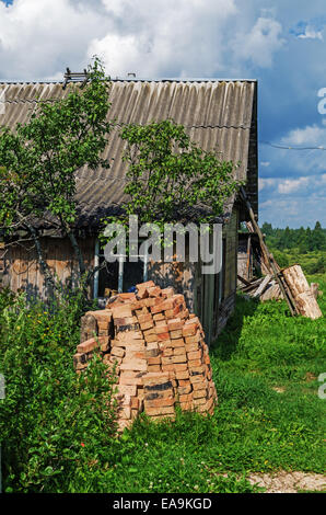 Altes Holzhaus und roten Ziegeln im Dorf. Stockfoto