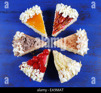 Thanksgiving-Apfel, Pekannuss, Kirsche, Karamell, Kürbis Gewürz und Schokoladen-Sahne Käsekuchen Kuchen auf dunklem Blau Vintage Holz Stockfoto