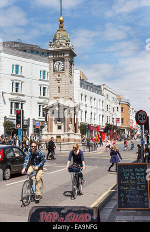 Radler vor der Uhrturm an der Kreuzung der Queens Road und Nordstraße, Brighton, eine verkehrsreiche Kreuzung das Herzstück des Stockfoto