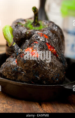 drei frische Paprika Charcol verbrannten über alten Holztisch auf eine skillett Stockfoto