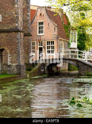 Fußgängerbrücke über einen Kanal im Zentrum von Delft, Niederlande, direkt hinter den dicken Mauern der Nieuwe Kerk ("Neue" Kirche) Stockfoto