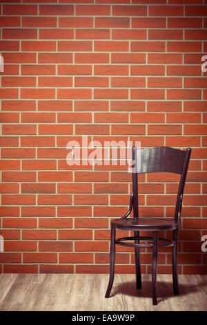 der Holzstuhl vor Backsteinmauer Stockfoto