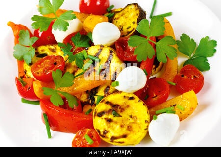 Gegrilltes Gemüse mit Mozzarella-Käse. Cherry-Tomaten, Paprika, Auberginen, Zucchini in weißen Teller mit frischen Kräutern serviert. Stockfoto
