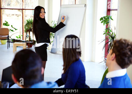 Glücklich Geschäftsfrau etwas auf Flipchart präsentieren Stockfoto