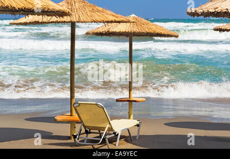 Land Meeresstrand mit Sonnenschirmen und Liegestühlen auf dem Hintergrund von stürmischer See. Stockfoto