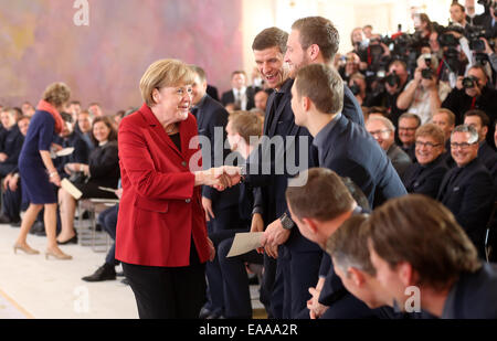 Berlin, Deutschland. 10. November 2014. Deutsche Bundeskanzlerin Angela Merkel (CDU) grüßt Nationalmannschaft Fußball-Spieler Thomas Mueller (C) und Shkodran Mustafi im Schloss Bellevue in Berlin, Deutschland, 10. November 2014. Die deutsche Fußball-Nationalmannschaft ist mit dem Award "Silbernes Lorbeerblatt" ausgezeichnet, für den Gewinn der WM 2014 in Brasilien. Bildnachweis: Dpa picture Alliance/Alamy Live News Stockfoto