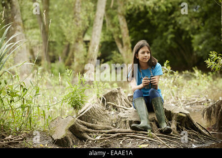 Mädchen-Vogelbeobachtung. Sitzen auf einem Baumstumpf halten Ferngläser. Stockfoto