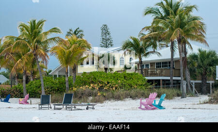 Bunte hölzerne Liegestühle mit Palmen vor Strandhäuser Stockfoto