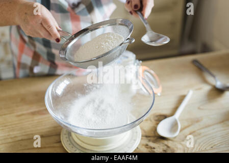 Eine Frau Mess- und weißes Mehl durchsieben. Zuhause backen. Stockfoto