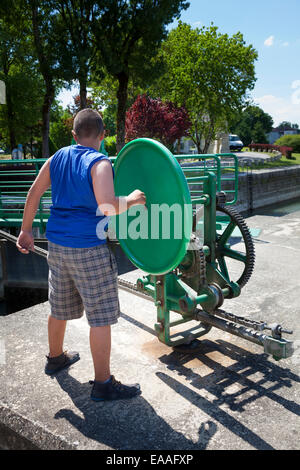 Ein Junge, der Betrieb der Schleuse Öffnungsmechanismus Rad auf dem Fluss Charente in Jarnac Stockfoto