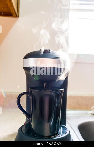 Dampf steigt aus einer einzigen Tasse Kaffeemaschine Stockfoto