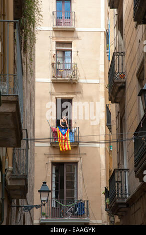 junge Frau Aufhängen von Wäsche auf dem Balkon drapiert mit katalanischen Flagge in der gotischen Viertel von Barcelona, Katalonien, Spanien Stockfoto