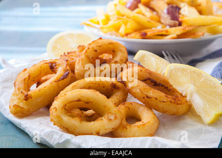 einige Calamari Ringe tief gebraten mit Zitrone und Pommes frites Stockfoto