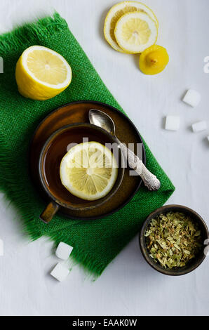Linden Tee in braunen Tasse mit Zitronen in weißes Tuch Stockfoto