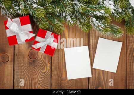 Weihnachts-Geschenk-Box und leere Bilderrahmen über hölzerne Hintergrund mit Schnee Tanne Stockfoto