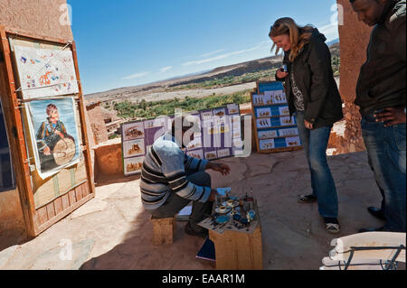 Horizontale Porträt eines Künstlers zeigt ein Tourist sein Werk zum Verkauf in Ait Benhaddou Stockfoto