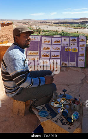 Vertikale Porträt eines Künstlers zeigt ein Tourist sein Werk zum Verkauf in Ait Benhaddou Stockfoto