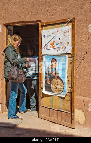 Vertikale Porträt eines Künstlers zeigt ein Tourist sein Werk zum Verkauf in Ait Benhaddou Stockfoto