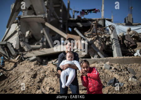 Gaza, Al-Schadschaija Nachbarschaft. 9. November 2014. Palästinensische Yousef Saudi, 12, seine Schwester ROOA Saudi, 6 und ihren jüngsten Bruder Uday Saudi, 4 Monate sind in der Nähe von den Trümmern ihres zerstörten Hauses in Al-Schadschaija Nachbarschaft, östlich von Gaza-Stadt am 9. November 2014 gesehen. Palästinensische Kinder übergeben eine harte Zeit während der 50-DayIsraeli-Operation im Gaza-Streifen in diesem Sommer. Über 500 Kinder in Gaza getötet wurden und 3.000 wurden verletzt. Es gibt mehr als 40.000 Familien blieben Vertriebenen. Der Konflikt hatte 1.500 Waisen hinterlassen. © Wissam Nassar/Xinhua/Alamy Live-Nachrichten Stockfoto