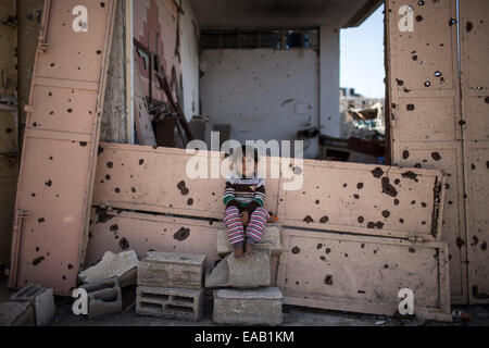 Gaza, Al-Schadschaija Nachbarschaft. 9. November 2014. Ein palästinensisches Kind sitzt Abed Hassanein, 3, über den Trümmern der zerstörten Haus in Al-Schadschaija Nachbarschaft, östlich von Gaza-Stadt am 9. November 2014. Palästinensische Kinder übergeben eine harte Zeit während der 50-DayIsraeli-Operation im Gaza-Streifen in diesem Sommer. Über 500 Kinder in Gaza getötet wurden und 3.000 wurden verletzt. Es gibt mehr als 40.000 Familien blieben Vertriebenen. Der Konflikt hatte 1.500 Waisen hinterlassen. © Wissam Nassar/Xinhua/Alamy Live-Nachrichten Stockfoto