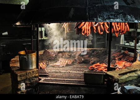 Texas Style Barbecue Pit Würstchen und Bruststück Rauchen über eine riesige offene Flamme. Stockfoto