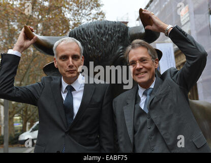 Frankfurt Main, Deutschland. 11. November 2014. Juergen Behrend (R), Vorsitzender-/ Co-Präsidenten Mgmt Board bei Hella KG Hueck & Co. und Hella CEO Rolf Breidenbach (L) stehen vor der Stier-Skulptur vor dem Börsengang von Hella bestand außerhalb der Deutschen Börse in Frankfurt Main, Deutschland, 11. November 2014. Das Lager wurde an 27,50 Euro angeboten. Foto: ARNE DEDERT/Dpa/Alamy Live-Nachrichten Stockfoto