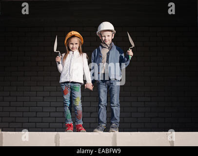 kleine Jungen und Mädchen in Helme bauen Haus Stockfoto