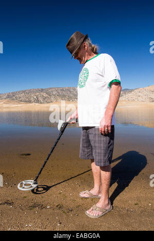 Ein Mann nutzt seine Metalldetektor auf den Seegrund des Lake Isabella in der Nähe von Bakersfield, östlich von kalifornischen Central Valley, die bei weniger als 13 % Kapazität nach dem vier Jahr lang verheerende Dürre. Das Reservoir sank so tief, dass der Wasserstand unterhalb der Ablaufrohr. Stockfoto