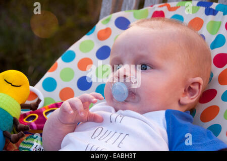 Baby Junge sitzt in Türsteher Stuhl mit Spielzeug spielen Stockfoto