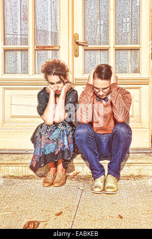 deprimiert und aufgeregt, Mann und Frau kauert vor dem Haus im Treppenhaus, weil Probleme sie haben Stockfoto