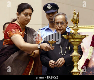 Neu-Delhi, Indien. 11. November 2014. Indian Human Ressource Minister Smriti Irani (L) leuchtet eine traditionelle Lampe wie indischen Präsidenten Pranab Mukherjee im Rahmen einer Veranstaltung anlässlich der National Education Day in New Delhi, Indien, 11. November 2014 blickt auf. Bildnachweis: Partha Sarkar/Xinhua/Alamy Live-Nachrichten Stockfoto