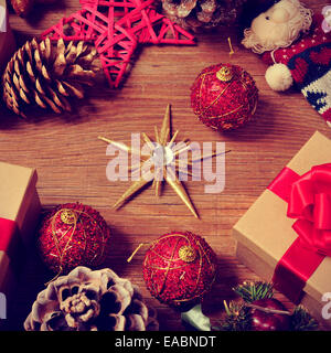 ein Haufen Geschenke und Weihnachtsschmuck, wie Christbaumkugeln und Sternen, auf einem rustikalen Holztisch Stockfoto