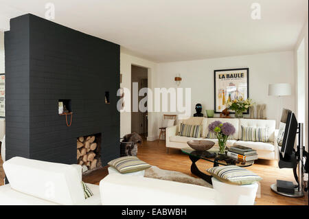 Großen weißen Knöpfen Sofa mit gestreiften Kissen im Wohnzimmer mit bemalten Wand und Log Backsteinhaus