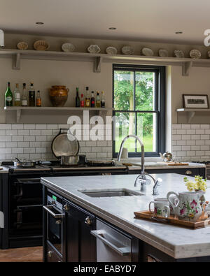 Landhausküche mit Marmor-Arbeitsplatten, Aga und offenen Regalen. Die Schränke sind von Farrow & Ball in Off-schwarz lackiert. Stockfoto